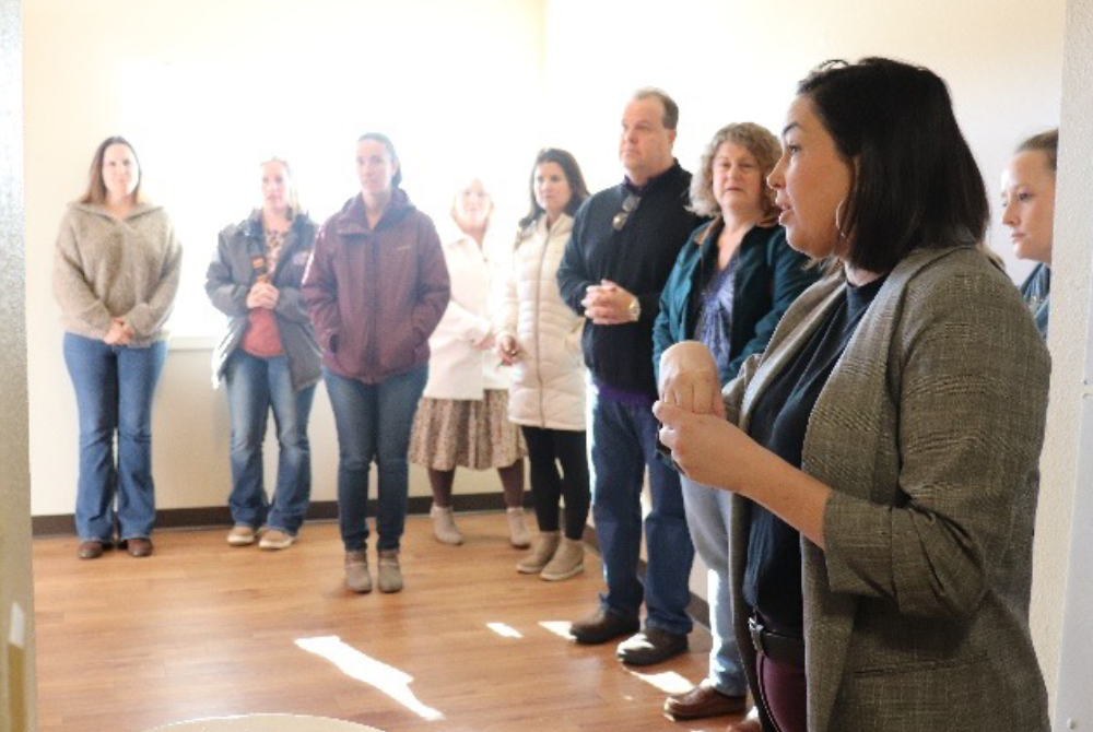 Figure 2: Employees stand in the living room of a renovated apartment at The Timbers.